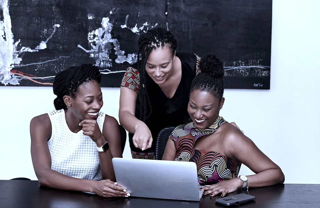 Three colleagues reviewing work on a laptop